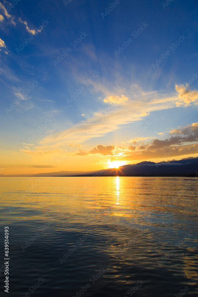 Beautiful cloudy sunset over the sea and mountains. Bright sky in the rays of the orange sun. natural texture Beautiful cloudy sunset over the sea and mountains. Bright sky in the rays of the orange sun. natural texture