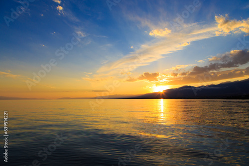 Beautiful cloudy sunset over the sea and mountains. Bright sky in the rays of the orange sun. natural texture