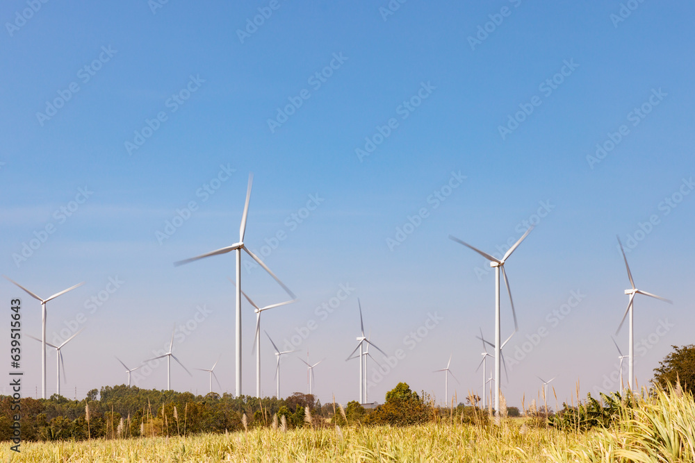 Field of wind turbines with motion blur on their blade using long exposure during sunny day and blue sky Field of wind turbines with motion blur on their blade using long exposure during sunny day and blue sky