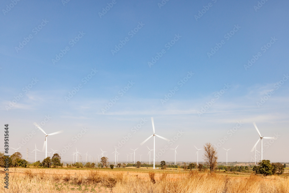 Field of wind turbines with motion blur on their blade using long exposure during sunny day and blue sky Field of wind turbines with motion blur on their blade using long exposure during sunny day and blue sky