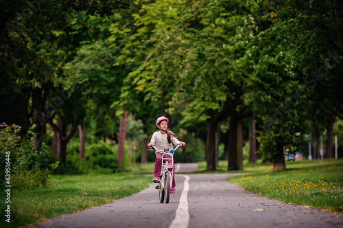 Wallpaper Mural Little schooler girl riding bike in parks. Summer time, wearing helmet. From the back. Torontodigital.ca
