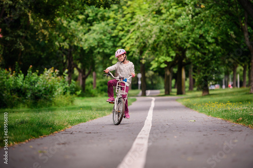 Wallpaper Mural Little schooler girl riding bike in parks. Summer time, wearing helmet. From the back. Torontodigital.ca
