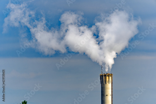 Concrete chimney of waste incineration plant with white smoke on a cloudy summer morning at City of Zürich, Switzerland.