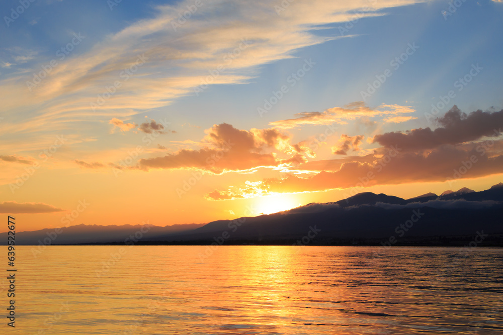 Colorful sunset on the sea. Mountain lake in the rays of the orange sun. Kyrgyzstan, Lake Issyk-Kul. Colorful sunset on the sea. Mountain lake in the rays of the orange sun. Kyrgyzstan, Lake Issyk-Kul.