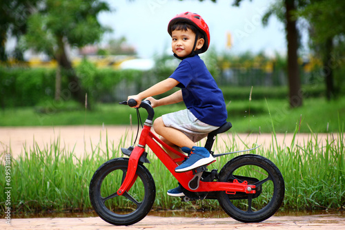 Asian Little boy riding a red bicycle in park