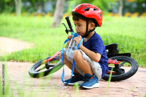 Asian Little boy riding a red bicycle in park
