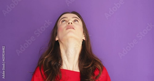 Young lady is shocked and disappointed and rolling eyes in the studio on purple background. She is looking very upset, mad, tired and angry. Woman wear red long sleeves rolling eyes.