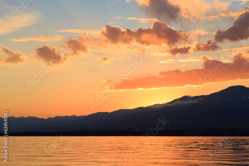 Colorful sunset on the sea. Mountain lake in the rays of the orange sun. Kyrgyzstan  Lake Issyk-Kul.