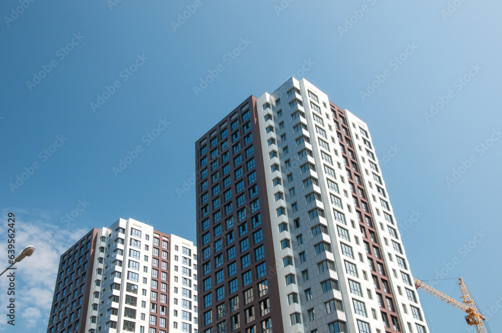 Unrecognizable facades of modern residential buildings under construction with blue sky in the background