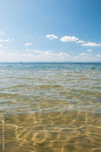 Seascape view of lake Uvildy in summer with unrecognizable supboarder in the background, South Urals, Russian Federation photo