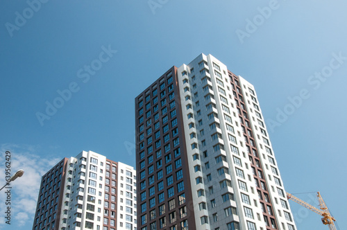 Unrecognizable facades of modern residential buildings under construction with blue sky in the background © Nickola_Che
