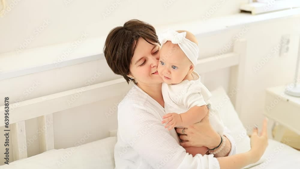 a young mother gently hugs her child kissing and admiring him, a happy family, mom and baby on the bed playing and having fun, maternal love and care, a happy mom on maternity leave a young mother gently hugs her child kissing and admiring him, a happy family, mom and baby on the bed playing and having fun, maternal love and care, a happy mom on maternity leave
