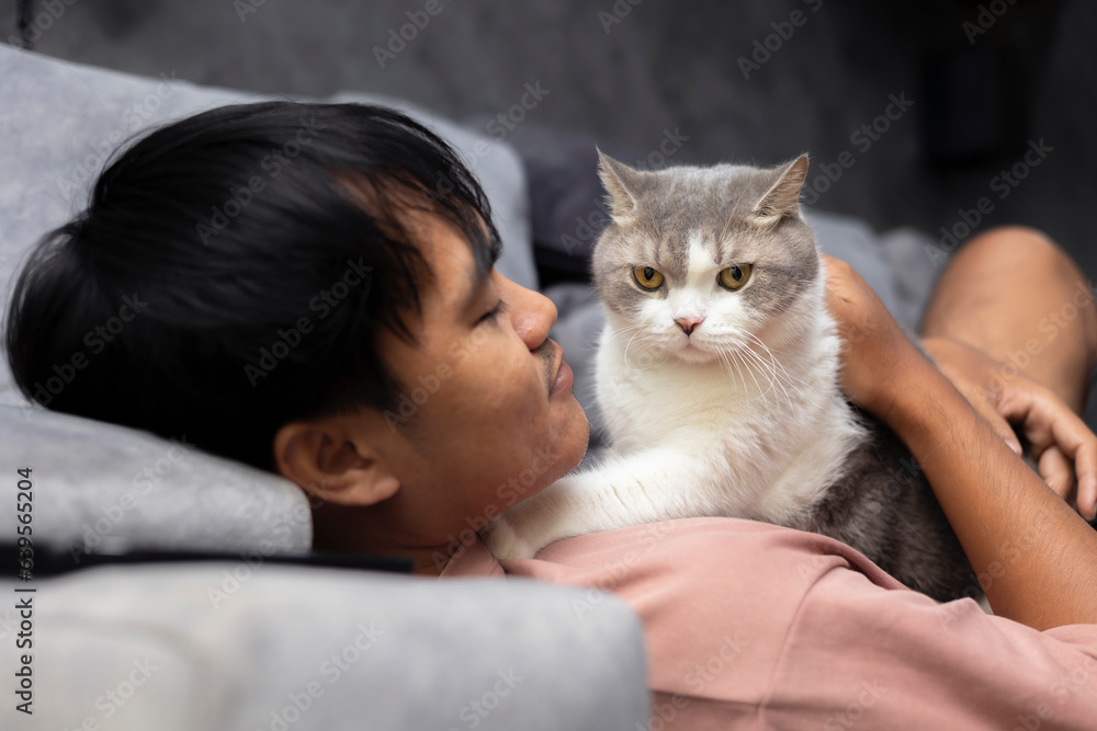 Asian man holding cat with black background. Asian man hugging a cat to show love for pets. Asian man holding cat with black background. Asian man hugging a cat to show love for pets.