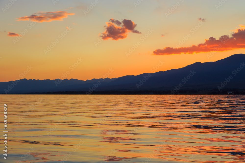 Beautiful cloudy sunset over the sea and mountains. Bright sky in the rays of the orange sun. natural texture Beautiful cloudy sunset over the sea and mountains. Bright sky in the rays of the orange sun. natural texture