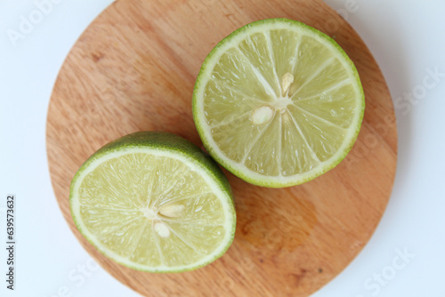 Halves of Green Lime, on wooden base, isolated on white background