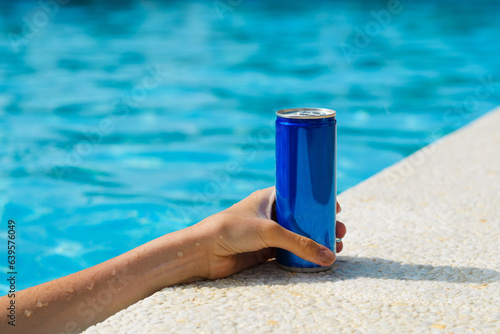 Hand with a can of cold drink by the pool. Summer vacation. Good service concept. Close-up