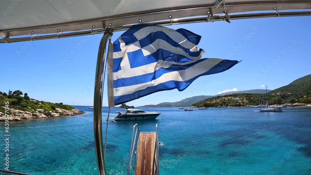Greek flag on boat cruise around the island of Ithaki or Ithaca in the Ionian sea in the Mediterranean sea of Greece