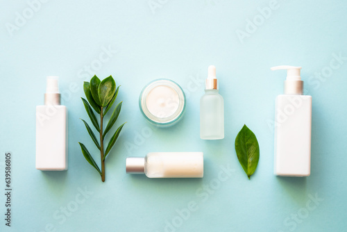 Natural cosmetic products. Cream, serum, tonic with green leaves. Top view on blue background.