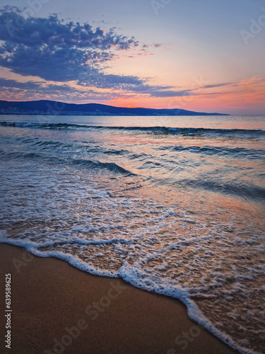 Fototapeta Naklejka Na Ścianę i Meble -  Dawn at the sea with foamy waves on the sand and colorful sky at the horizon. Sunny Beach coastline in Bulgaria. Summer and travel background