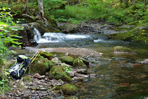 Hiking trail crossing a small creek. Backpack and hiking poles on river bank. Perfect spot to take a break photo