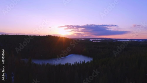 Drone flying over a frozen lake and forest in a beautiful purple sunset (Konnevesi National Park, Finland) photo