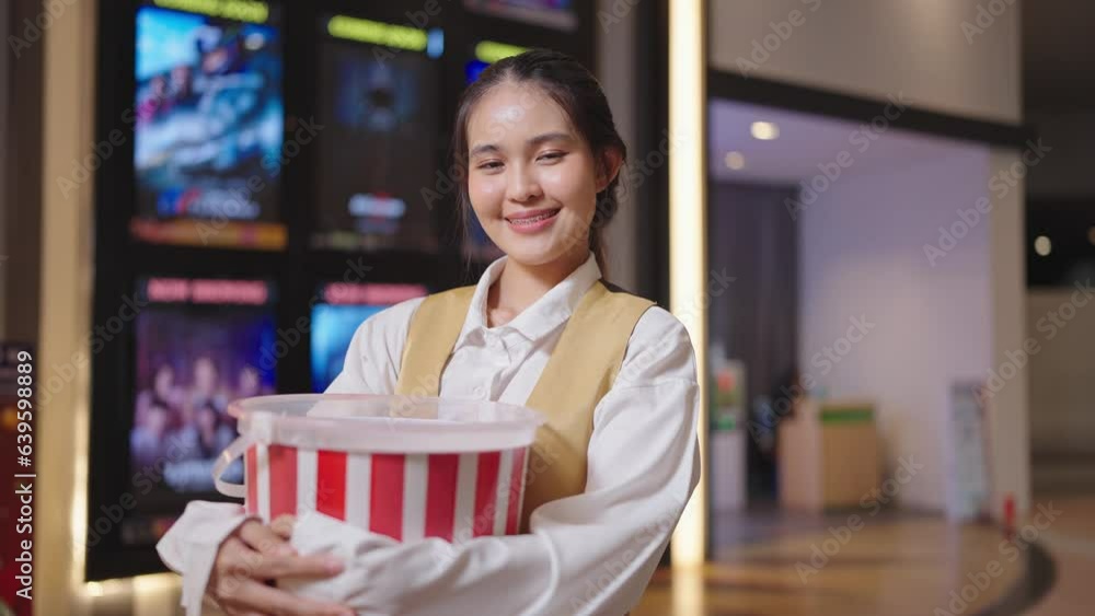 Beautiful young Asian woman movie theater staff in uniform holding