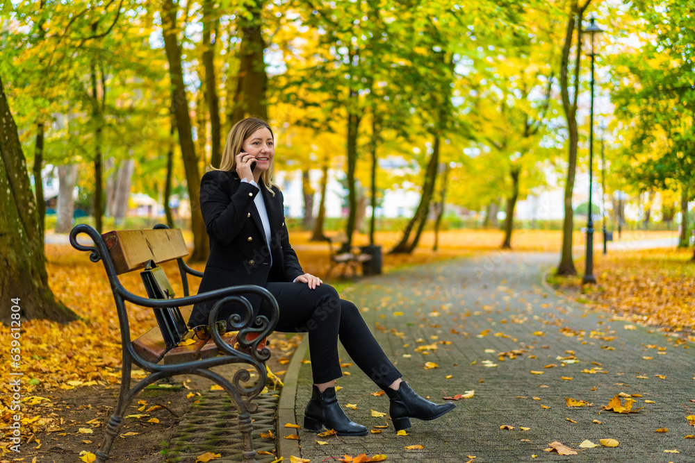 Beautiful woman talking on the phone sitting on bench in park
Beautiful woman talking on the phone sitting on bench in park