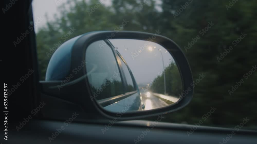 View in the Side Mirror of a Car that is Driving on the Urban Highway at dusk in the fog. View in the Rear View Side Mirror of Automobile, Driving a Blue Car along the Road Travel and Trip Concept. View in the Side Mirror of a Car that is Driving on the Urban Highway at dusk in the fog. View in the Rear View Side Mirror of Automobile, Driving a Blue Car along the Road Travel and Trip Concept.