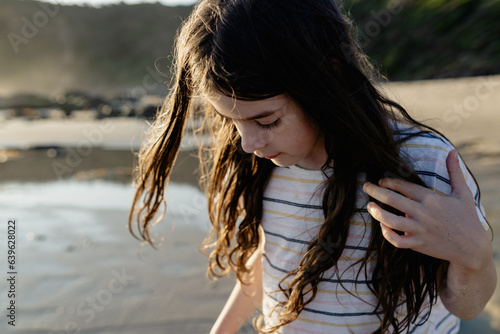 Portrait of a young girl with windswept hair on the beach at sunset photo