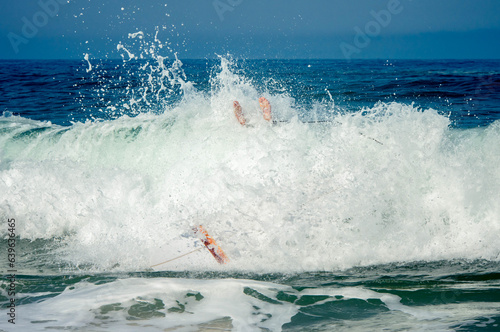 Middle-aged man in surf getting hit by a wave (with feet sticking out of splashes) photo