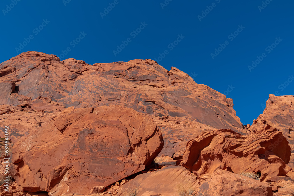 Panoramic view of red Aztek sandstone rock formations in Petroglyph Canyon along Mouse Tank hiking trail in Valley of Fire State Park in Mojave desert, Nevada, USA. Hot temperature in arid vegetation