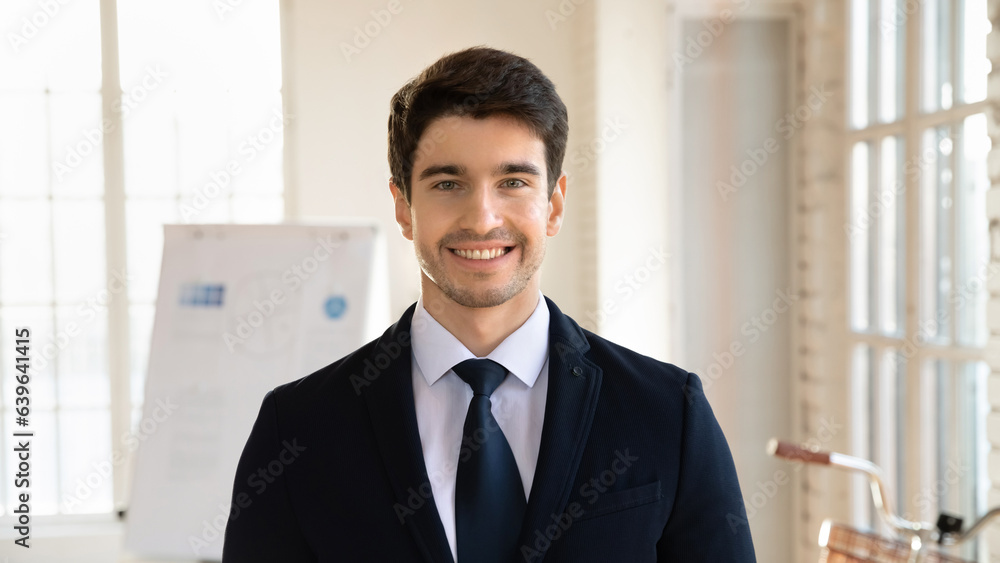 Close up headshot portrait of smiling young Caucasian businessman in formal suit look at camera posing in office, profile picture of male boss or employee show confidence success at workplace Close up headshot portrait of smiling young Caucasian businessman in formal suit look at camera posing in office, profile picture of male boss or employee show confidence success at workplace