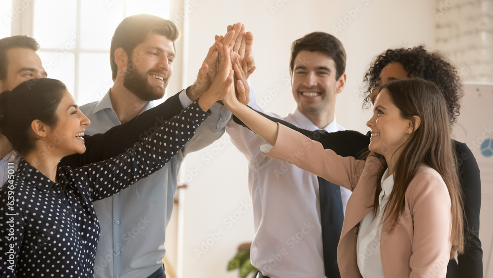 Excited multiracial employees give high five engaged in teambuilding ...