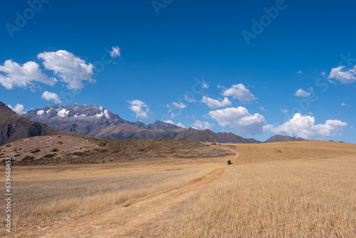 Landscapes of the Andes near the Maras Salt Flats in Peru with a green campervan driving on a dirt road