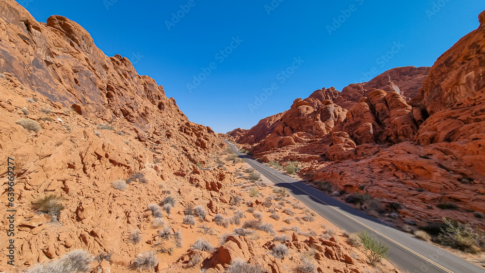 Panoramic view of endless winding empty Mouse tank road in Valley of Fire State Park through canyons of red Aztec Sandstone Rock formations and desert vegetation in Mojave desert, Overton, Nevada, USA