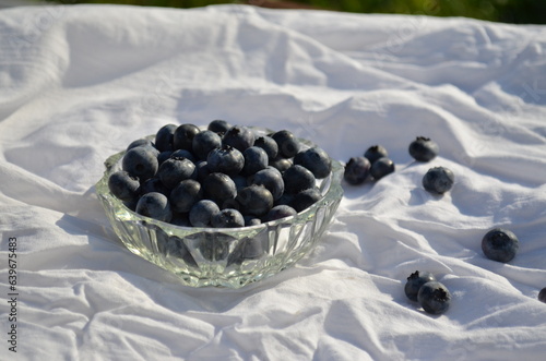 transparent saucer with scattered blueberries on a white cloth
