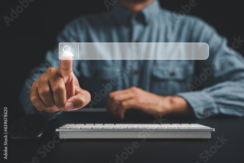 Obraz na płótnie Man's finger pointing at search icon on a dark background, using a computer keyboard for search engine optimization