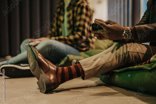 Smiling young multicultural friends playing with joysticks together at playing club photo