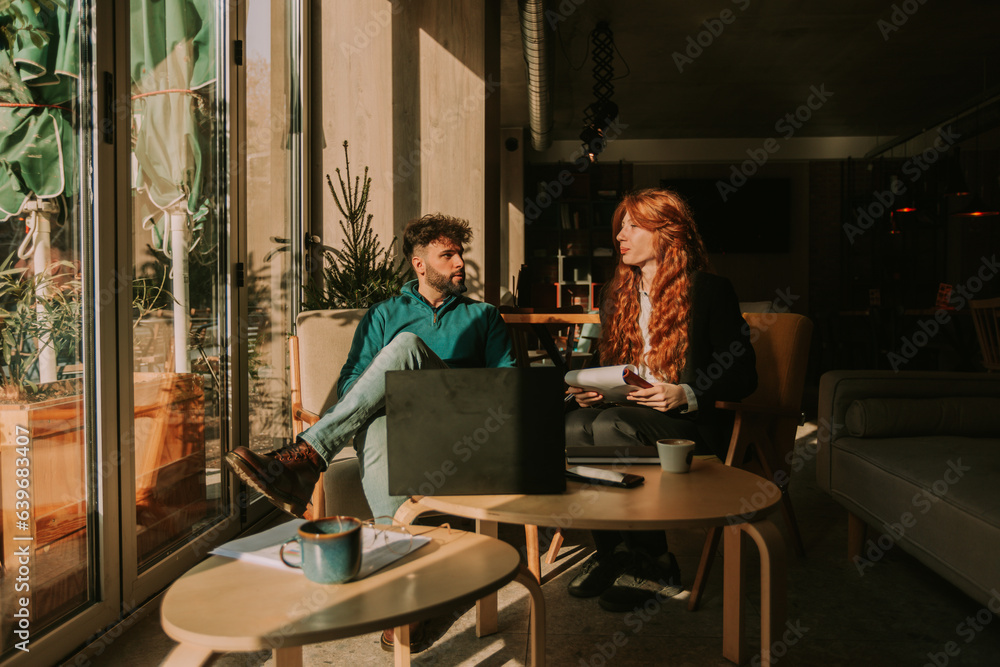 Beautiful young business couple talking business while working remotely at the coffee bar