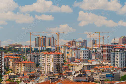 White clouds in the blue sky over working yellow construction cranes and apartment, residential buildings in Istanbul - daylight. Cityscape and architecture concept photo