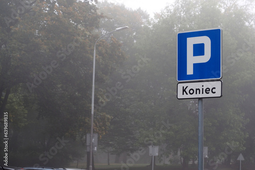 end parking sign on the background of the park in the fog. many trees in the park in the early morning
