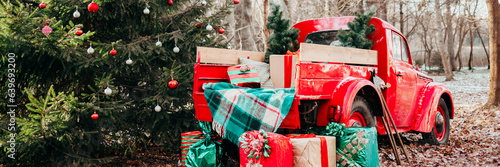 red car pickup truck decorated with Christmas wreath, blankets, pillows and gift boxes with presents is standing in forest, Santa Claus's magic transport, New Year and Christmas banner background