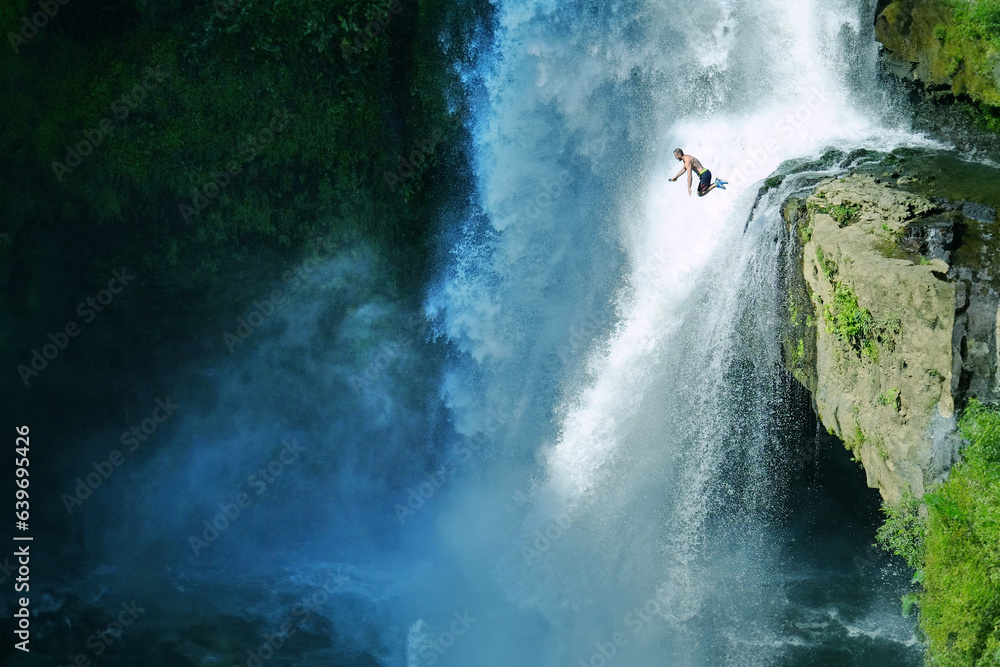 Jumping into the water. Man having fun at waterfalls in the nature. Bali, Indonesia Jumping into the water. Man having fun at waterfalls in the nature. Bali, Indonesia