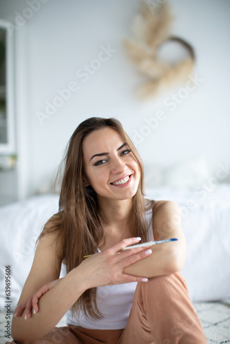 Closeup portrait of smiling female artist in cozy living room with paint brushes