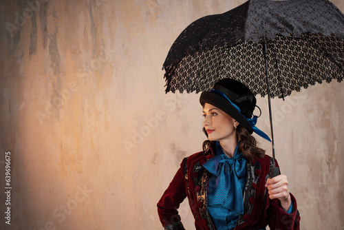 stylish lady in a burgundy old - fashioned suit with a hat and a lace umbrella . Brunette in a retro style suit