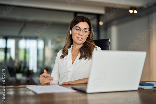 Mid aged business woman having hybrid meeting working in office. Busy mature female corporate leader executive, hr manager communicating by conference call, remote online job interview on laptop.