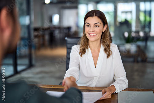 Smiling mature business woman hr handshaking hiring recruit at job interview. Happy mid aged professional bank manager, insurance agent, lawyer making contract deal with client at work office meeting.