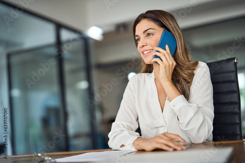 Confident mid aged business woman executive making business call in office. Smiling mature 40s female professional executive manager, lawyer or entrepreneur talking on cell phone at workplace. photo