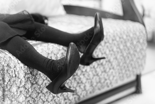The little girl tries on her mother's adult black shoes with a thin stiletto. photo