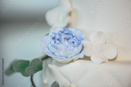 Gorgeous white wedding cake close up with blue and white fondant flowers and leaves